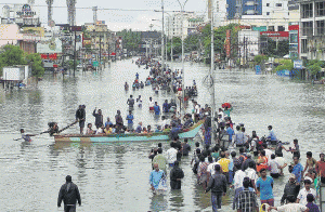 चेन्नई की पानी से भरी सड़क पार करते लोग 